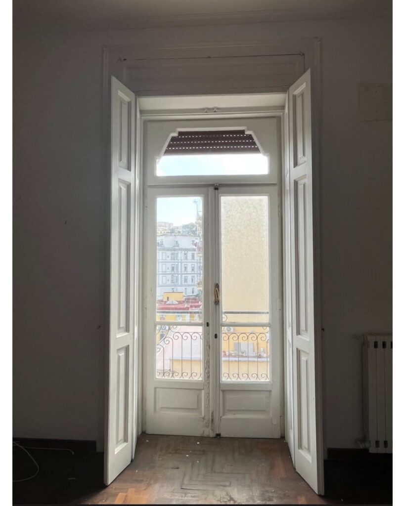 Portafinestra originale in legno con sopraluce sagomato nel centro storico di Napoli